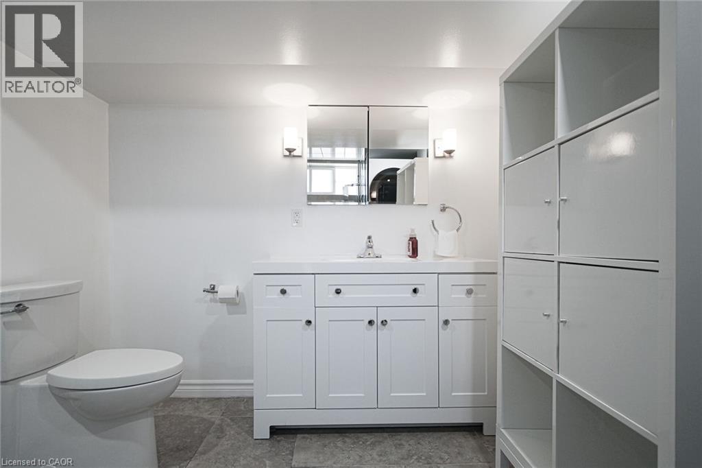 White shaker-style vanity with a single basin sink and wall-mounted sconces - 2105 Maplewood Drive, Burlington, ON - Indoor Photo Showing Bathroom