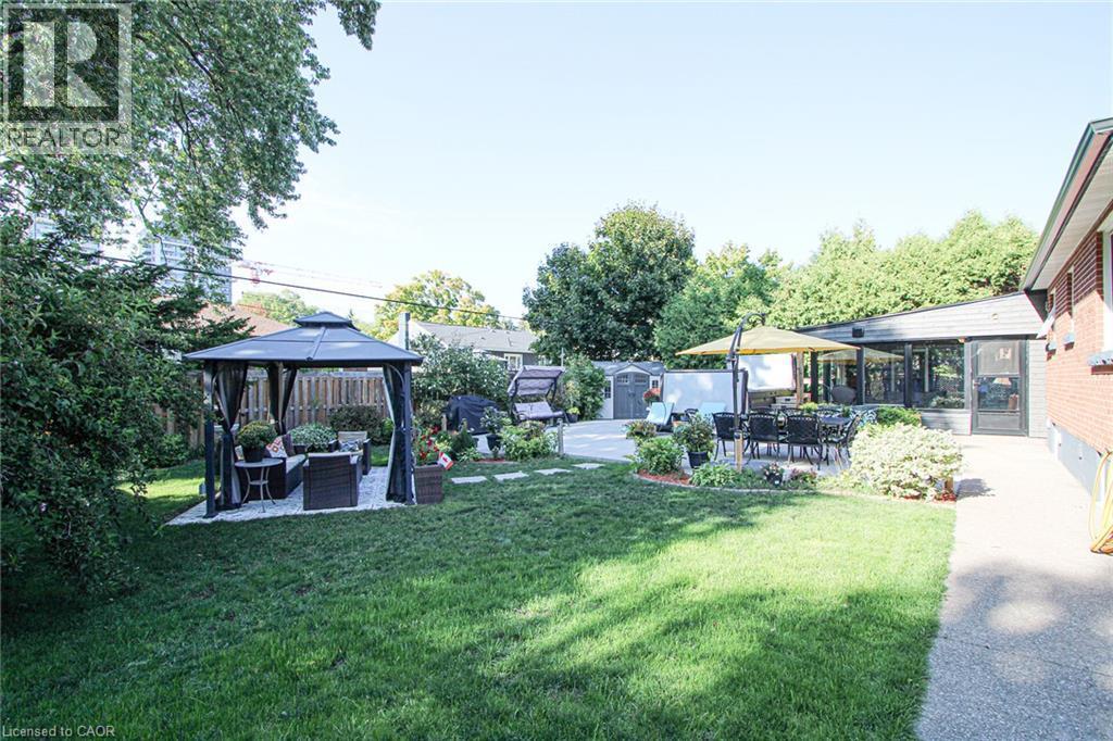 Expansive backyard featuring a lush lawn, a patio, and a sunroom extension - 2105 Maplewood Drive, Burlington, ON - Outdoor