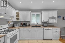 Kitchen featuring white cabinetry, a dual basin sink with a black faucet, light-toned countertops, and tile flooring - 