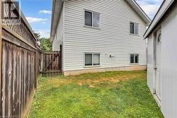 Rear exterior with horizontal siding and multiple windows, featuring a wooden privacy fence, a wooden gate, and a separate storage shed with an arched top door - 