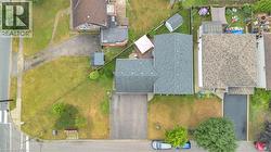 Aerial view showcasing the property's footprint with a dark shingle roof, paved driveway, and established green space - 
