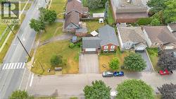Aerial perspective highlighting a red brick residence with an attached garage, a paved driveway, and mature landscaping - 