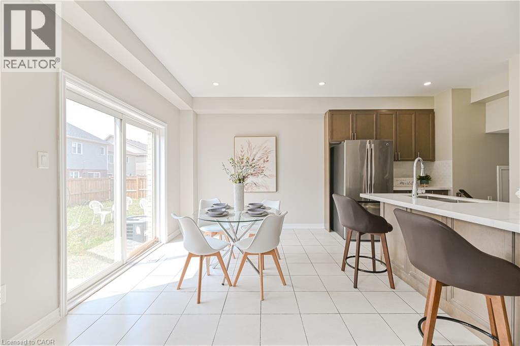 Open-concept kitchen and dining area featuring white tile flooring, stainless steel appliances, and a kitchen island with a light-colored countertop - 24 Weatherall Avenue, Cambridge, ON - Indoor