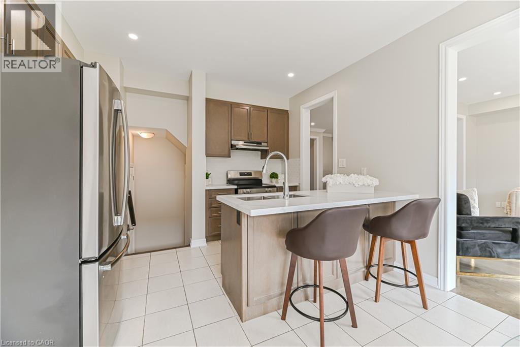 Kitchen featuring a central island with countertop, stainless steel appliances, wood-finish cabinetry, and tiled flooring - 24 Weatherall Avenue, Cambridge, ON - Indoor Photo Showing Kitchen