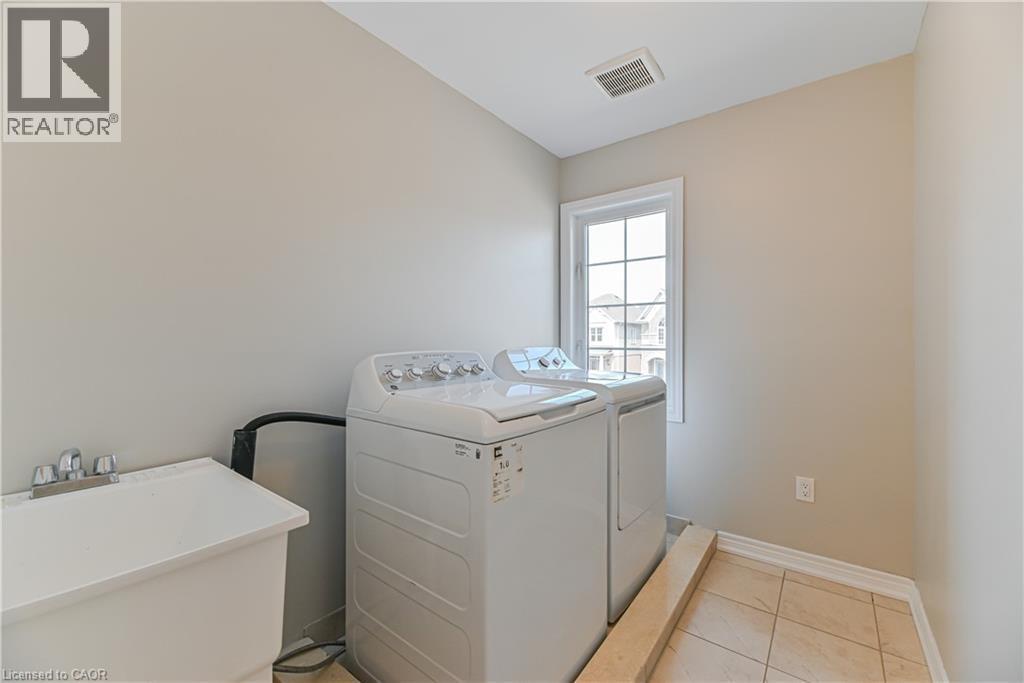 Utility sink, tiled flooring, window with grid panes, and neutral wall paint - 24 Weatherall Avenue, Cambridge, ON - Indoor Photo Showing Laundry Room
