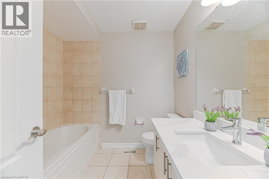 Bathroom featuring a built-in tub, tiled shower surround, integrated sink, and a large wall-mounted mirror - 24 Weatherall Avenue, Cambridge, ON - Indoor Photo Showing Bathroom