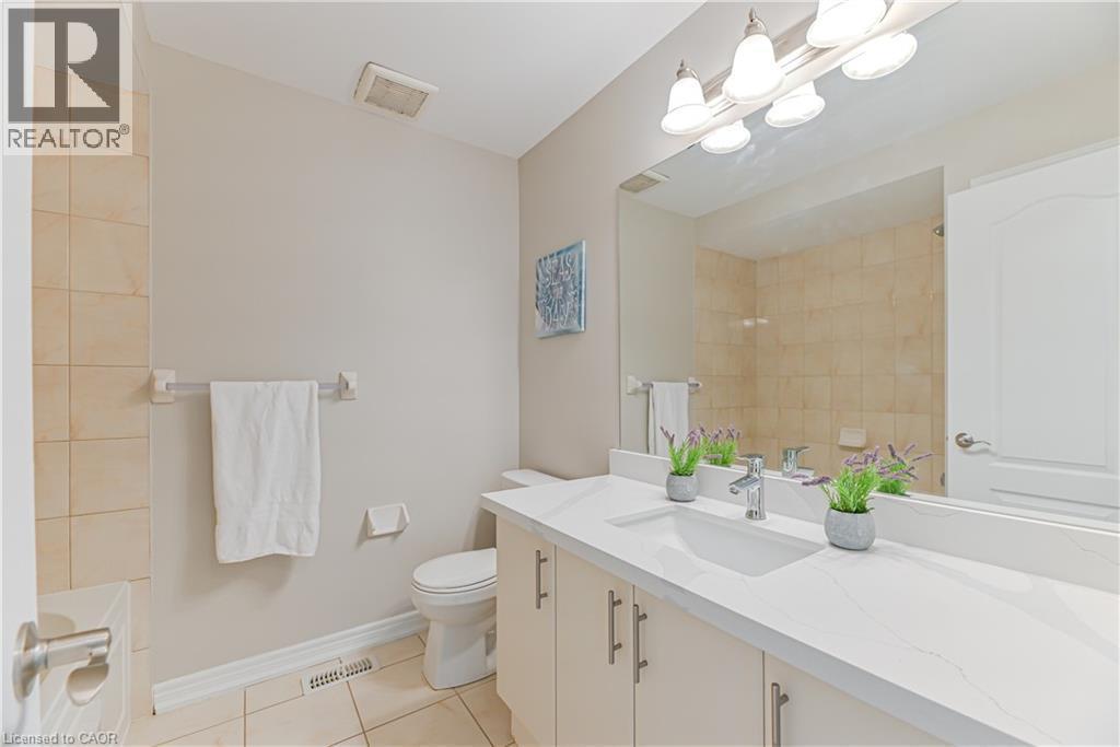 Bathroom featuring a single vanity with stone-finish countertop, undermount sink, and light-toned cabinetry - 24 Weatherall Avenue, Cambridge, ON - Indoor Photo Showing Bathroom