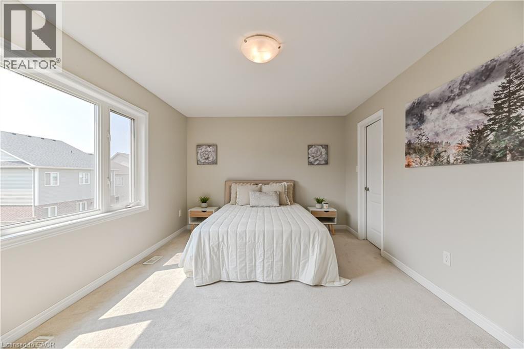 Neutral-toned carpeting and walls, large window with white trim, and a white interior door - 24 Weatherall Avenue, Cambridge, ON - Indoor Photo Showing Bedroom
