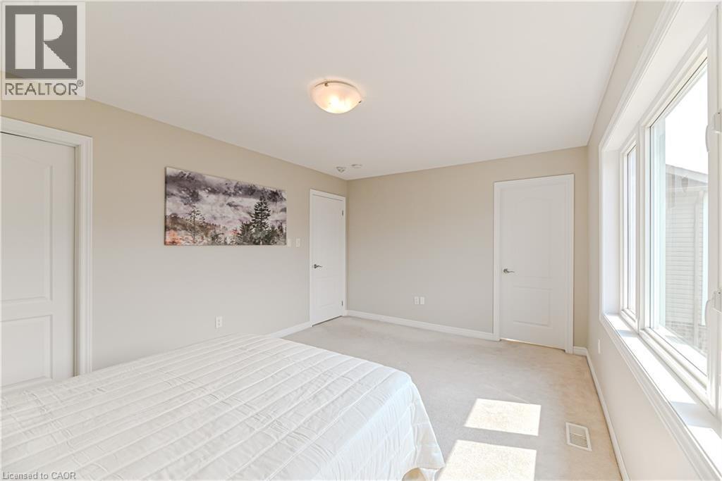 Neutral tone wall paint, carpet flooring, flush mount ceiling light fixture, multiple panel doors, and large multi-pane windows - 24 Weatherall Avenue, Cambridge, ON - Indoor Photo Showing Bedroom