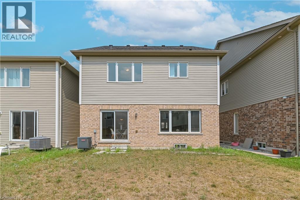 Rear exterior with a brick and siding facade, featuring upper-level windows and a ground-level sliding glass door - 24 Weatherall Avenue, Cambridge, ON - Outdoor With Exterior