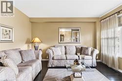 Recessed lighting, dark wood-finish flooring, light-toned walls, and window with sheer drapery - 