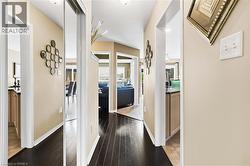Hallway with dark wood-finish flooring, light neutral wall paint, white trim, and a mirrored closet door - 