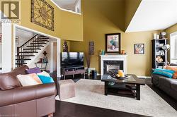 Hardwood flooring, two-story ceiling, white fireplace mantel with black surround, open archway, and staircase with dark wood banister - 