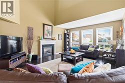 Vaulted ceilings, a built-in fireplace with a white mantel, dark wood-finish flooring, and multiple windows with blinds - 
