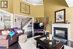 Vaulted ceiling living area with a dark wood-finish floor, a white mantel fireplace with a dark stone surround, and a staircase featuring dark wood treads and white risers - 