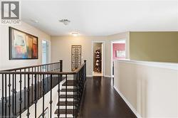 Staircase with dark wood finish treads and wrought iron balusters, complemented by dark wood finish flooring in the hallway - 