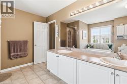 Dual basin vanity with white cabinetry, integrated tub, tiled shower enclosure, and tiled flooring - 