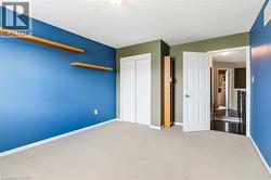 Carpeted room featuring built-in floating shelves, a paneled door, and a closet with sliding doors - 