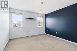 Neutral-toned carpet flooring, a dark accent wall, and two windows with blinds - 