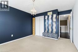 Recessed lighting, light-colored carpeting, built-in shelving, white bi-fold closet doors, and a decorative chandelier - 