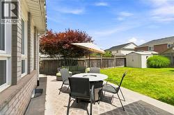 Expansive backyard featuring a concrete patio, a manicured lawn, and a wood privacy fence - 