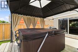 Covered outdoor spa with privacy curtains, wood deck, and concrete patio - 