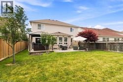 Expansive backyard with a manicured lawn, a concrete patio, and a raised wood deck - 