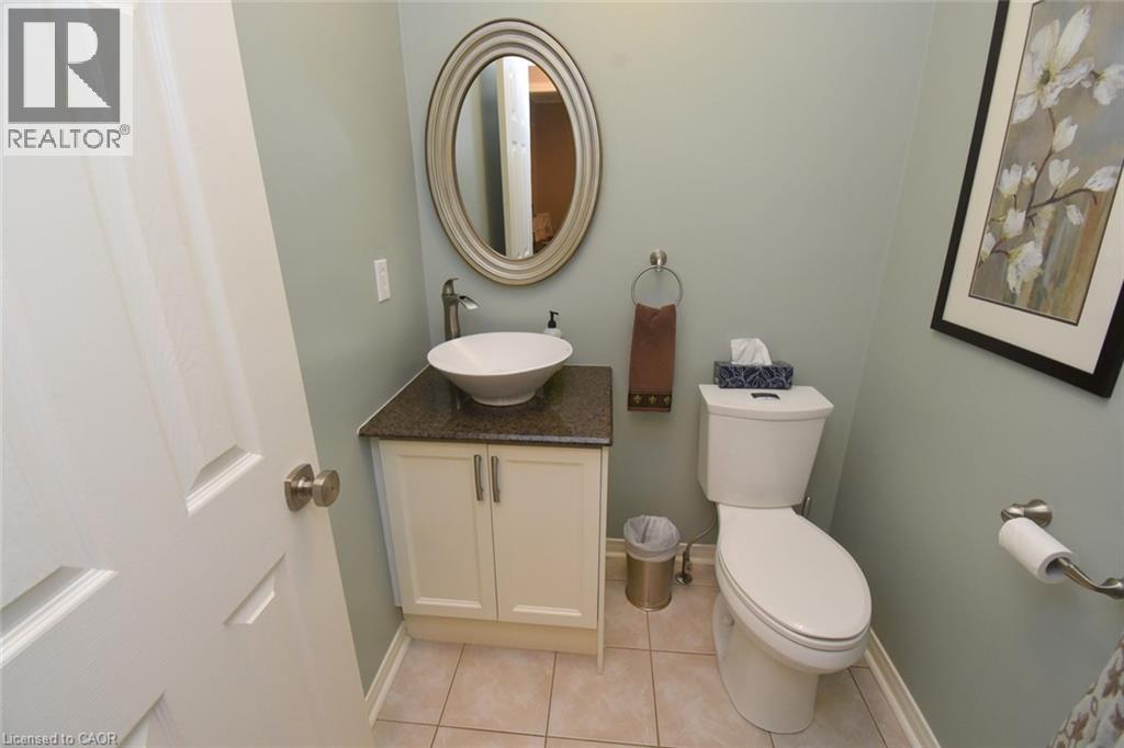 White shaker-style vanity with a vessel sink, dark countertop, and brushed nickel fixtures - 470 Amanda Crescent, Burlington, ON - Indoor Photo Showing Bathroom