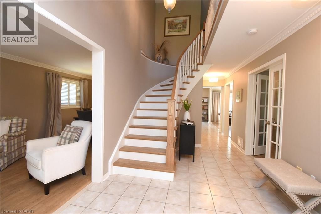 Curved staircase with wood treads and white risers, tile flooring, crown molding, and French doors - 470 Amanda Crescent, Burlington, ON - Indoor Photo Showing Other Room