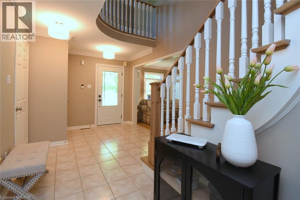 Welcoming foyer featuring a curved staircase with white balusters and wood handrail, ceramic tile flooring, recessed ceiling lighting - 470 Amanda Crescent, Burlington, ON - Indoor Photo Showing Other Room