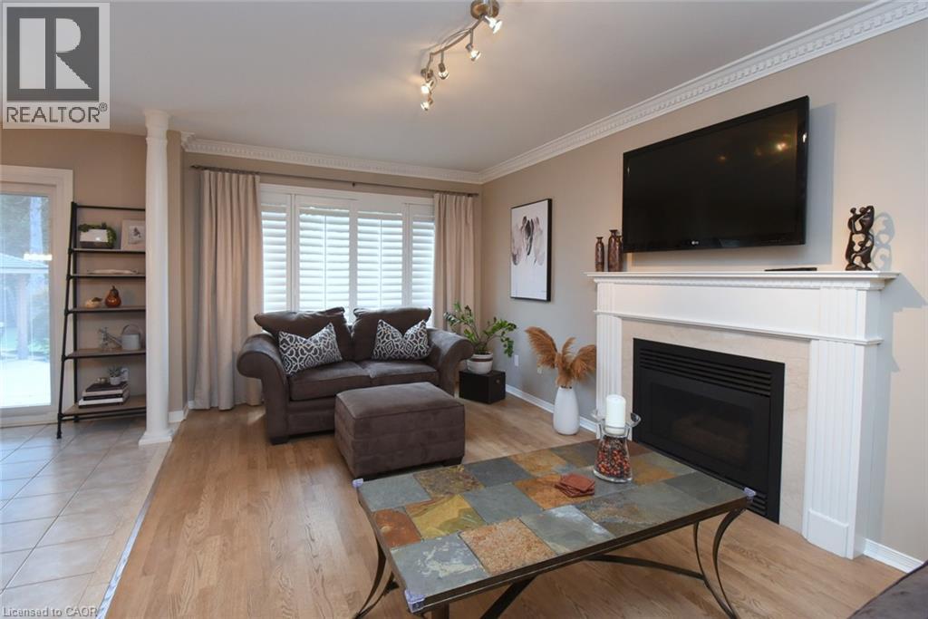 Fireplace with a classic white mantel, wood-finish flooring, white window shutters, and track lighting - 470 Amanda Crescent, Burlington, ON - Indoor Photo Showing Living Room With Fireplace