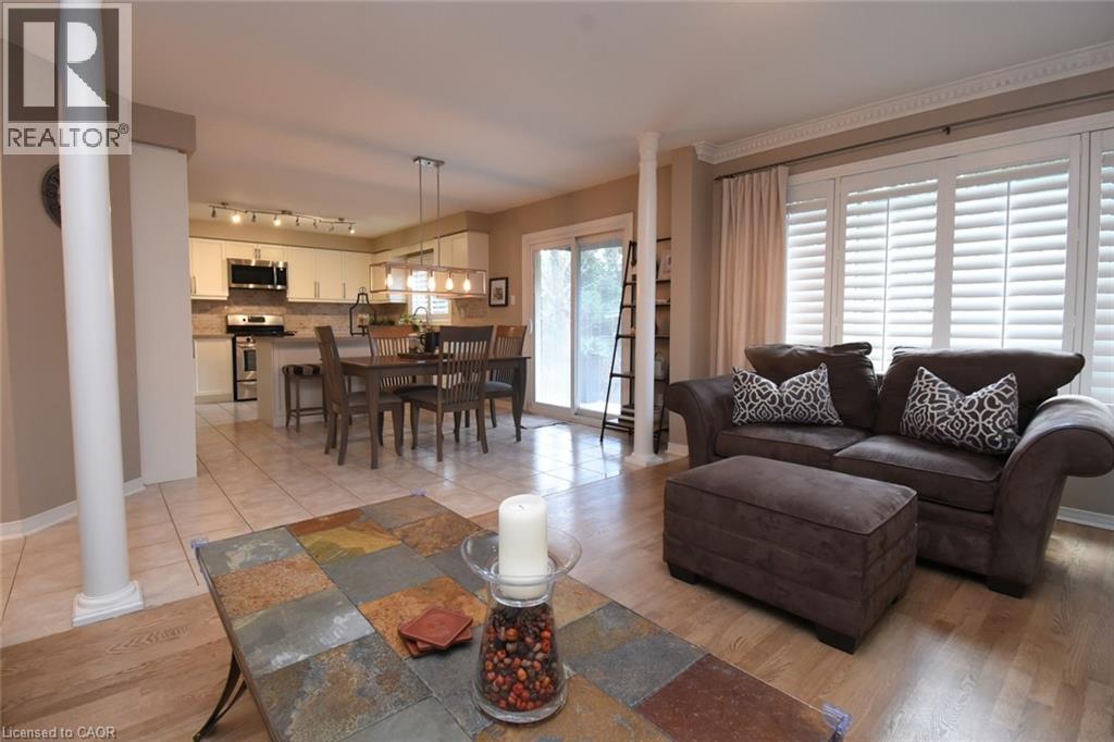 Hardwood-style flooring in the foreground, with tile flooring in the kitchen and dining area - 470 Amanda Crescent, Burlington, ON - Indoor Photo Showing Living Room