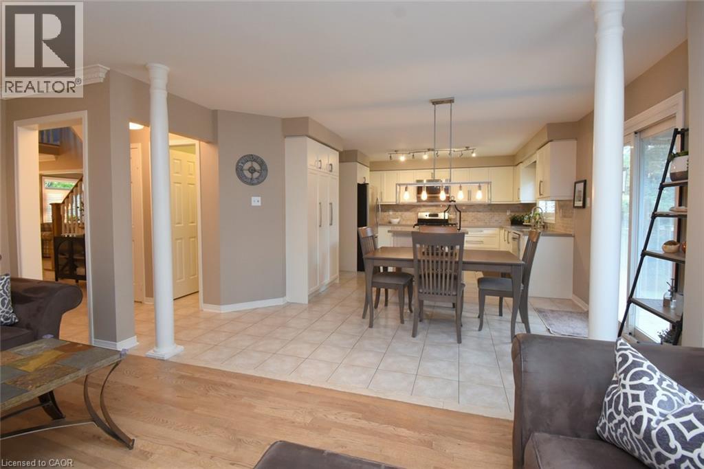 Open-concept living space with light wood-finish flooring, a kitchen featuring white cabinetry and a tile backsplash, and a dining area with tiled flooring - 470 Amanda Crescent, Burlington, ON - Indoor