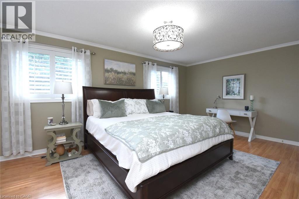 Recessed lighting, crown molding, wood-finish flooring, two windows with blinds, and a decorative ceiling fixture - 470 Amanda Crescent, Burlington, ON - Indoor Photo Showing Bedroom