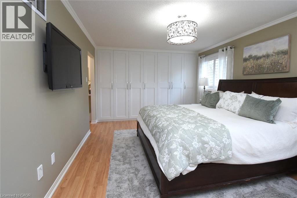 Wood-finish flooring, white built-in cabinetry, crown molding, and a drum-style ceiling light fixture - 470 Amanda Crescent, Burlington, ON - Indoor Photo Showing Bedroom