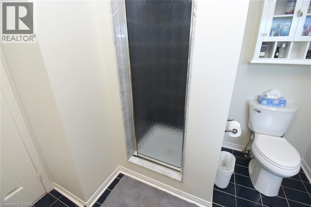 Frosted glass shower enclosure, white wall-mounted storage cabinet, and dark tiled flooring - 470 Amanda Crescent, Burlington, ON - Indoor Photo Showing Bathroom
