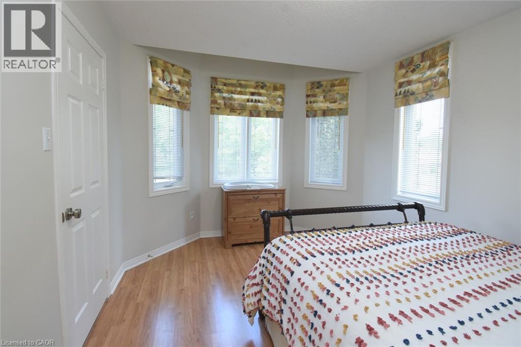 Bay window with three individual windows, wood-finish flooring, white paneled door, and neutral wall tones - 470 Amanda Crescent, Burlington, ON - Indoor Photo Showing Bedroom