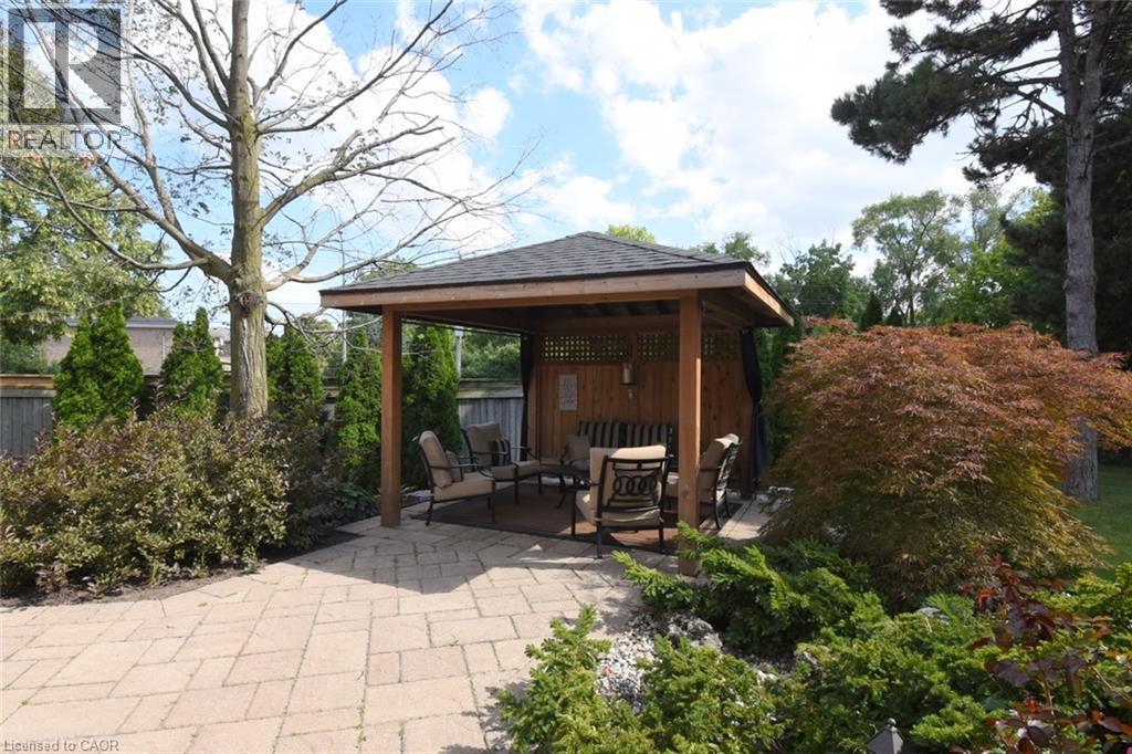 Paved patio with a wood-frame gazebo featuring a shingled roof and lattice side panels - 470 Amanda Crescent, Burlington, ON - Outdoor With Deck Patio Veranda
