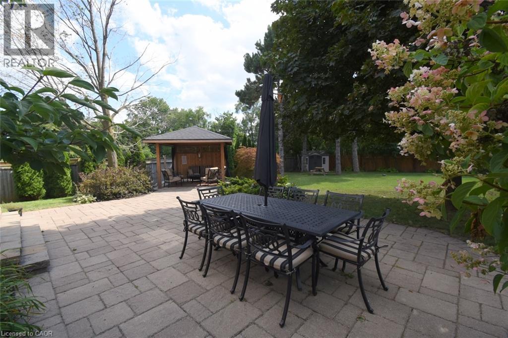 Expansive paver patio featuring a built-in wooden gazebo and a manicured lawn - 470 Amanda Crescent, Burlington, ON - Outdoor With Deck Patio Veranda