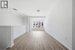 Open concept room featuring wood-finish flooring, white walls, and a large window - 