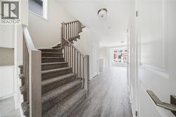 Elegant staircase featuring carpeted treads, wood-finish railings, and brushed metal hardware - 