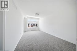 Bright interior space with light gray speckled carpeting, white painted walls, and a large multi-pane window - 