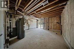 Unfinished basement space with exposed ceiling joists, concrete flooring, and a water heater installation - 