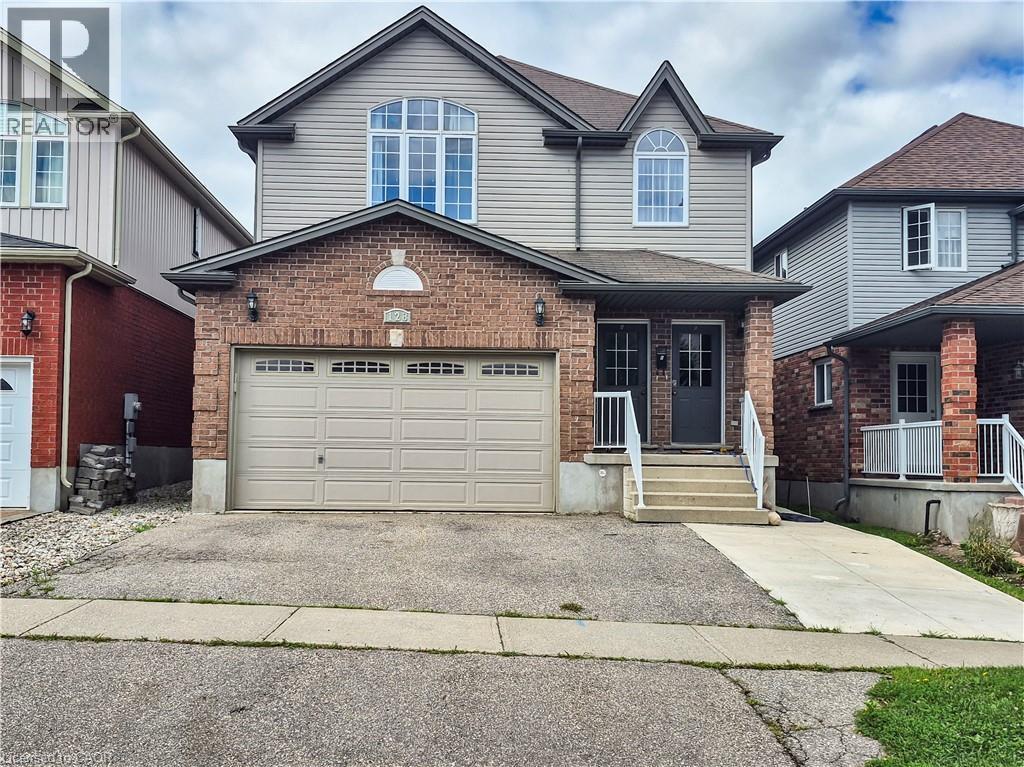 Two-story residence featuring brick and siding exterior, arched window accents, an integrated garage, and a covered entry with white railings - 128 Udvari Crescent Unit# A, Kitchener, ON - Outdoor With Facade