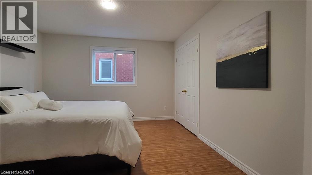 Recessed ceiling lighting, wood-finish flooring, white trim, and a white interior door with brass hardware - 128 Udvari Crescent Unit# A, Kitchener, ON - Indoor Photo Showing Bedroom