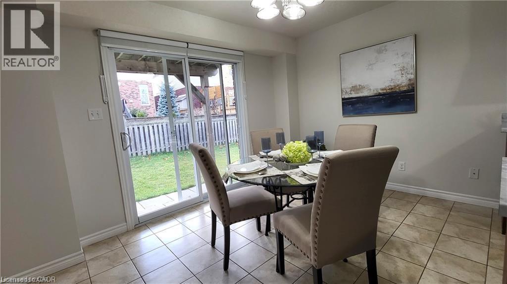 Tile flooring, sliding glass door, fenced backyard, and ceiling-mounted light fixture - 128 Udvari Crescent Unit# A, Kitchener, ON - Indoor Photo Showing Dining Room