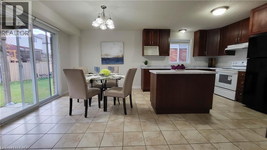 Kitchen featuring wood cabinetry, white appliances, and an island with a light-toned countertop - 128 Udvari Crescent Unit# A, Kitchener, ON - Indoor
