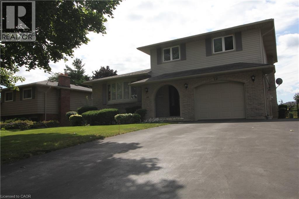 Multi-level residence featuring stone and siding exterior, arched entryway, attached garage, and mature landscaping - 14 Berkley Crescent, Simcoe, ON - Outdoor