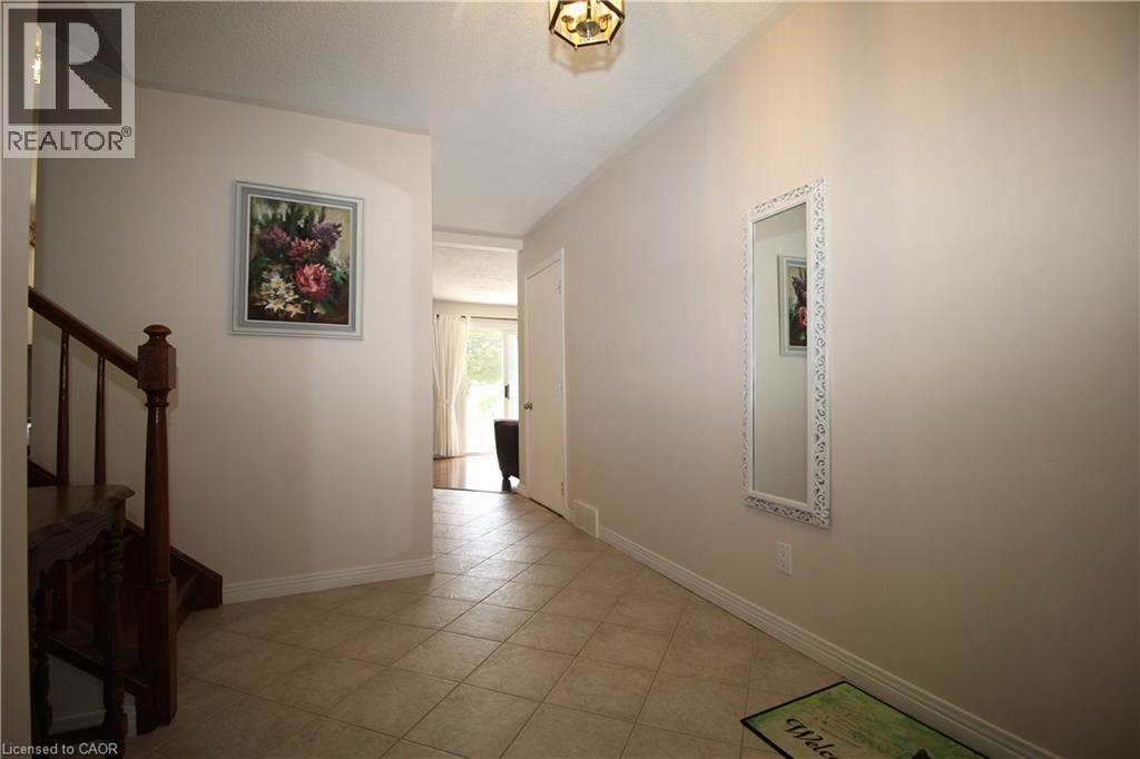 Entryway featuring neutral wall tones, tile flooring, a wooden staircase, and an overhead light fixture - 14 Berkley Crescent, Simcoe, ON - Indoor Photo Showing Other Room
