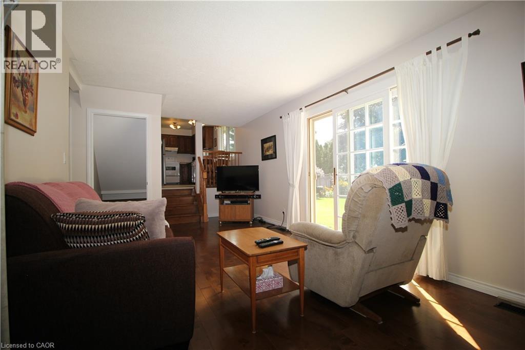 Hard-Wood flooring throughout, sliding glass door with transom windows, and white walls - 14 Berkley Crescent, Simcoe, ON - Indoor Photo Showing Living Room